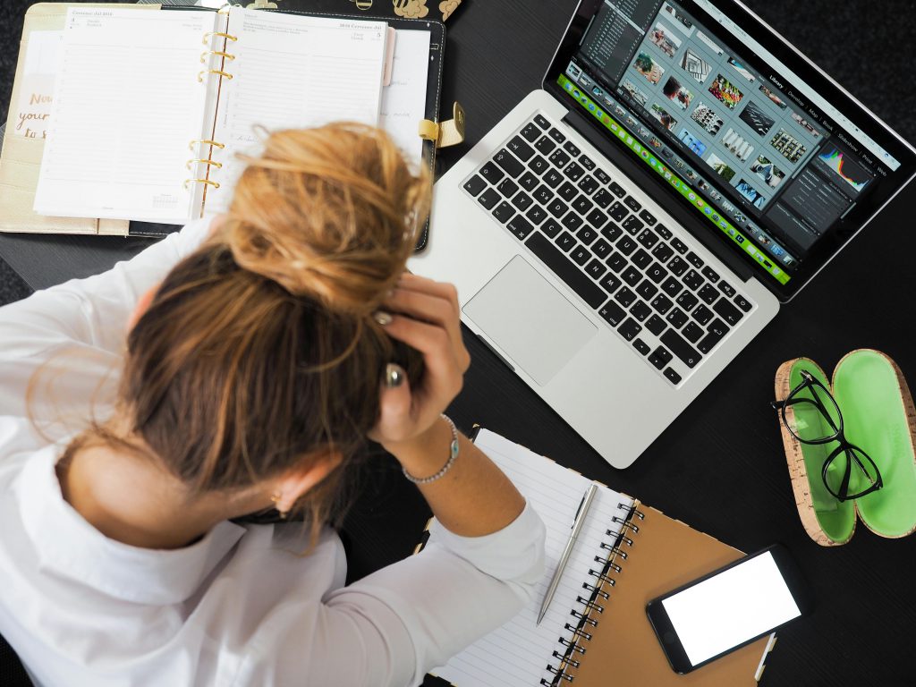 pexels photo 313690 313690 Overhead view of a stressed woman working at a desk with a laptop, phone, and notebooks.